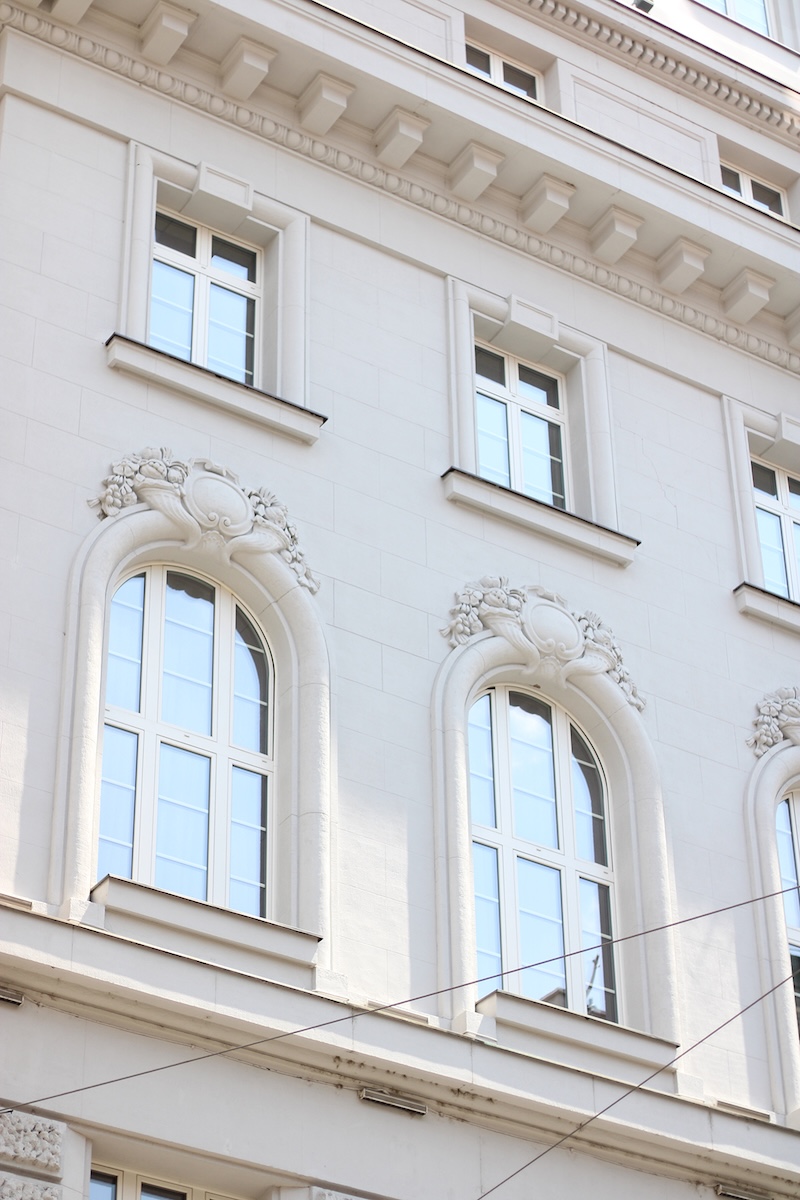 Photographie zoomée d'un bâtiment blanc aux grandes vitres reflétant un ciel bleu