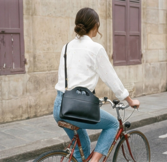 Une femme vue de dos sur un vélo de ville rouge avec le sac LUA N°1